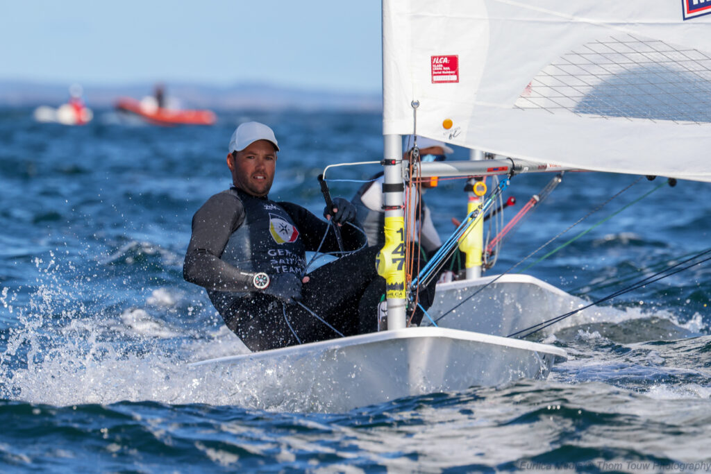 Philipp Buhl sitzt in seiner ILCA 7-Jolle. Das Segel ist weit geöffnet, die Sonne scheint, der Wind ist eher leicht. 