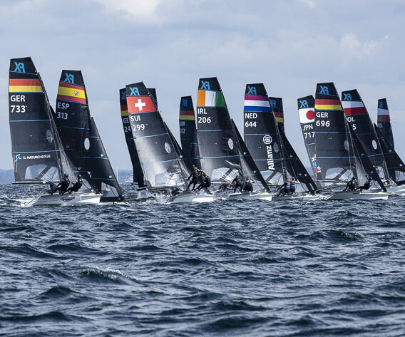 Viele Skiffjollen der 49erFX Klasse mit schwarzen Segeln und den Farben der verschiedenen Länder im oberen Teil der Segel.