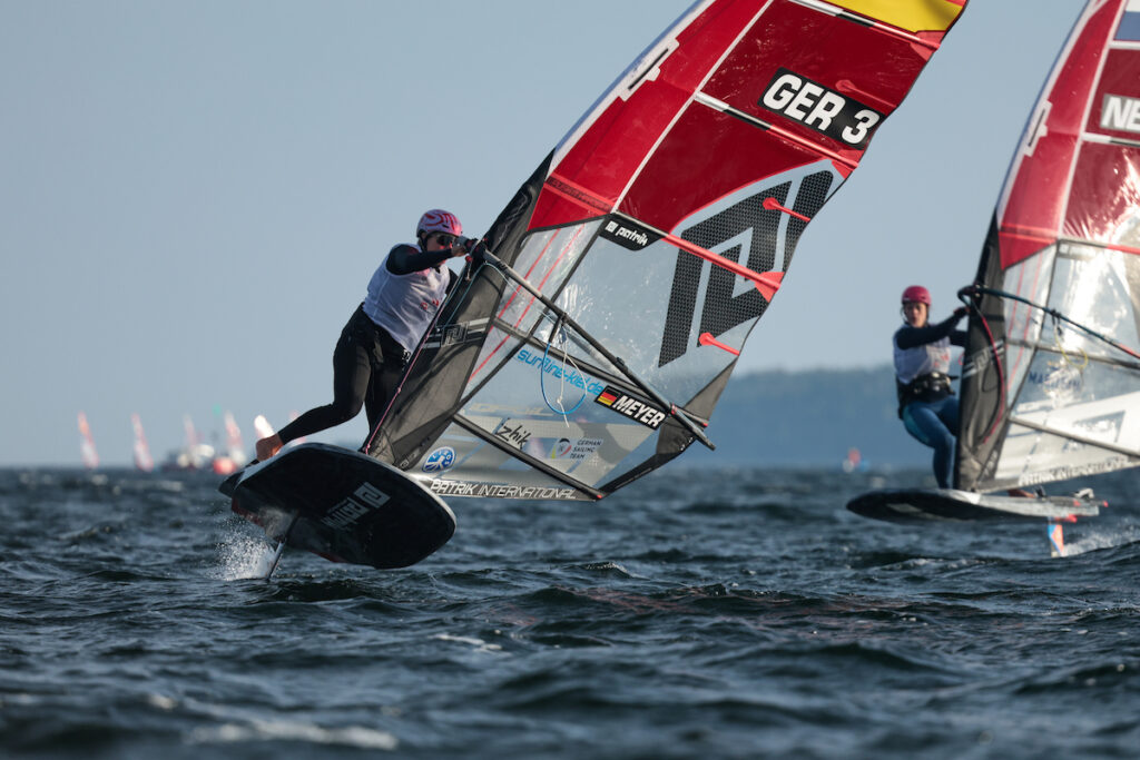 Eine Frau auf einem foilenden Surfboard vom Typ iQFOiL