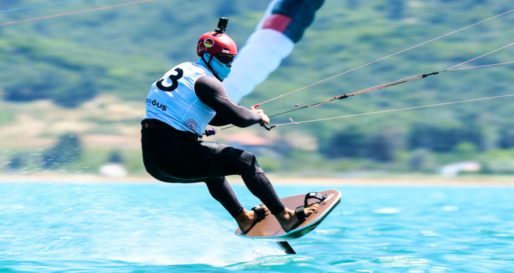 Jan Vöster aus dem German Sailing Team auf seinem Formula Kite-Board. Er schützt sein Gesicht mit einem Tuch gegen die Sonne. Auf dem Helm trägt er eine Kamera.