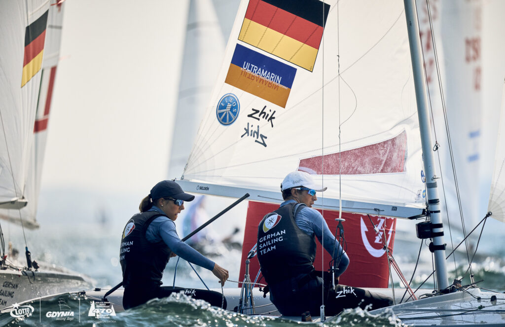 Eine Frau und ein Mann auf einer 470er-Jolle, sie tragen die Trikots vom German Sailing Team.