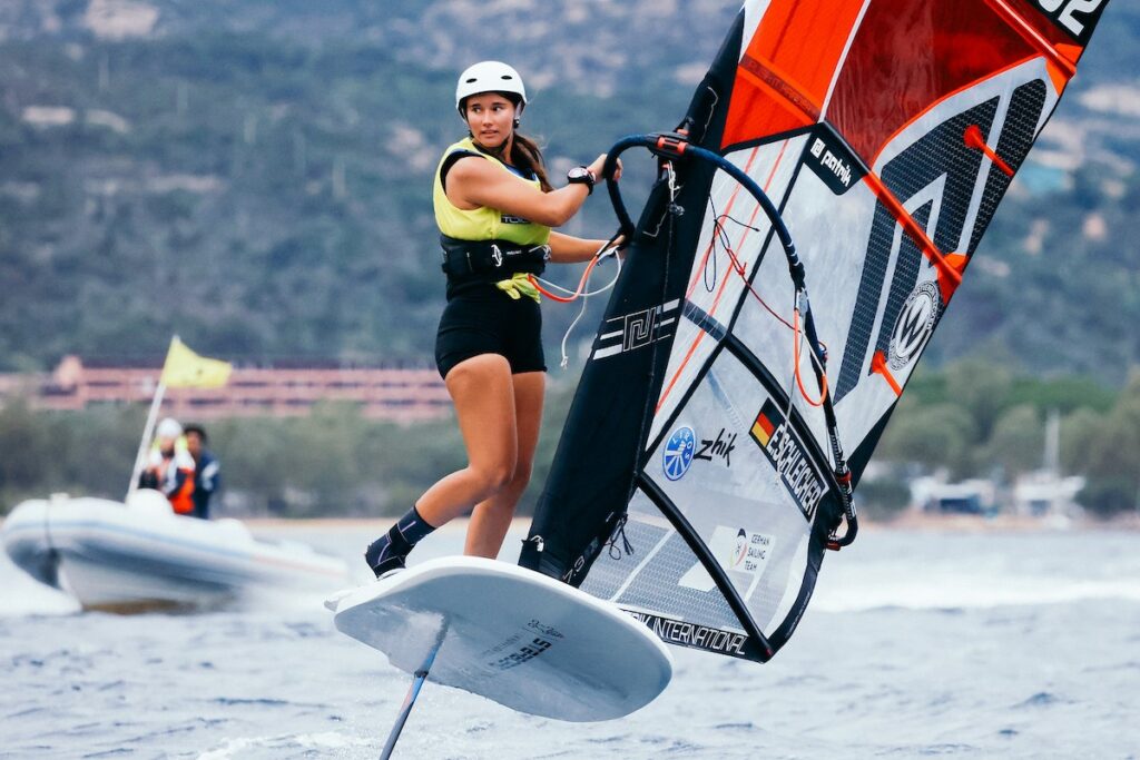 Eine Frau auf einem foilenden Windsurfboard.