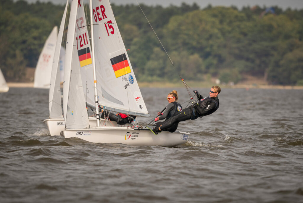 Zwei Segler auf einer 470er Jolle, im Segel ist die deutsche Flagge zu erkennen, dazu die Segelnummer 15. Auf dem weißen Rumpf steht German Sailing Team.