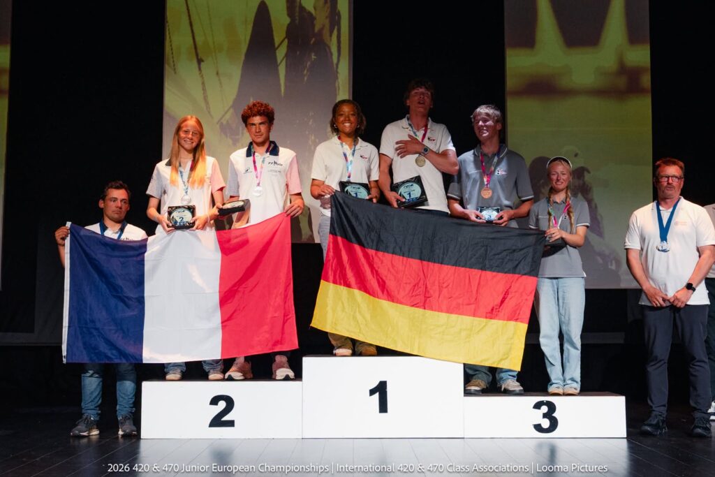 Sechs junge Menschen mit den Flaggen von Deutschland und Frankreich in den Händen stehen auf einem Podium