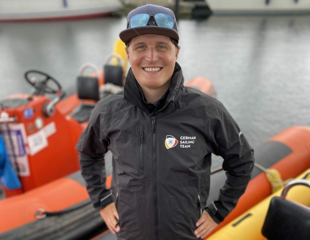 Moritz Klingenberg steht auf einem Motorboot und lächelt in die Kamera