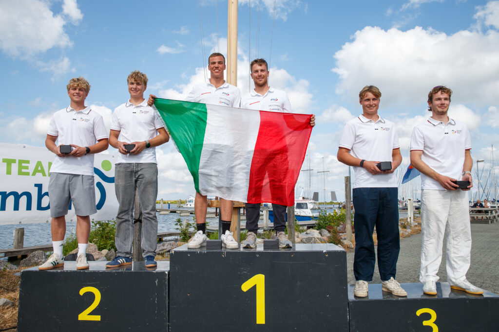 Sechs Männer auf einem Podest die Mittleren heben eine italienische Flagge hoch